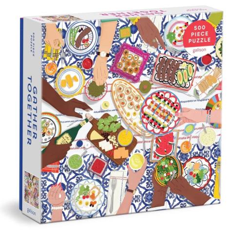 A jigsaw puzzle box with an image by Maja Tomljanovic titled, "Gather Together" and depicts a Mediterranean influenced vignette of friends and family gathering together at the table.