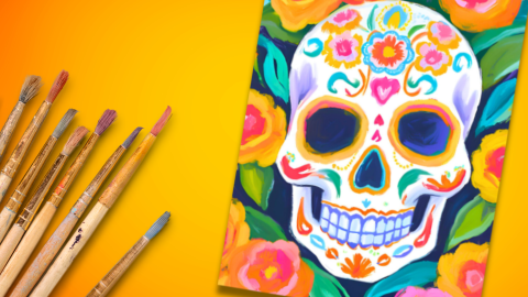 Colorful sugar skull painting with marigold flowers around the skull and paint brushes next to the canvas.