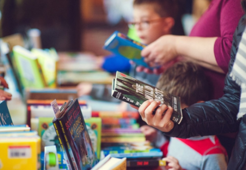 Adults and kids browsing a table full of books.