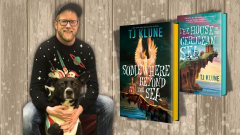 Picture of author TJ Klune wearing a hat, glasses, and black Christmas sweater, posing with a black dog. The cover of two books, "The House in the Cerulean Sea" and "Somewhere Beyond the Sea" are displayed.