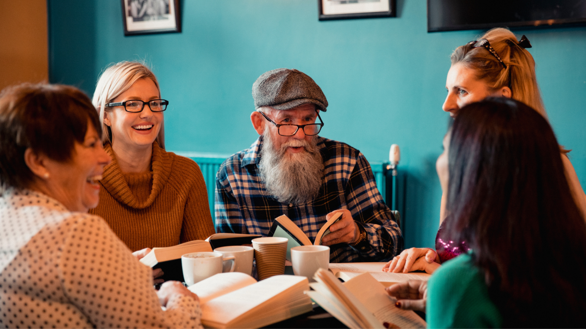 Happy group of people holding books and talking.