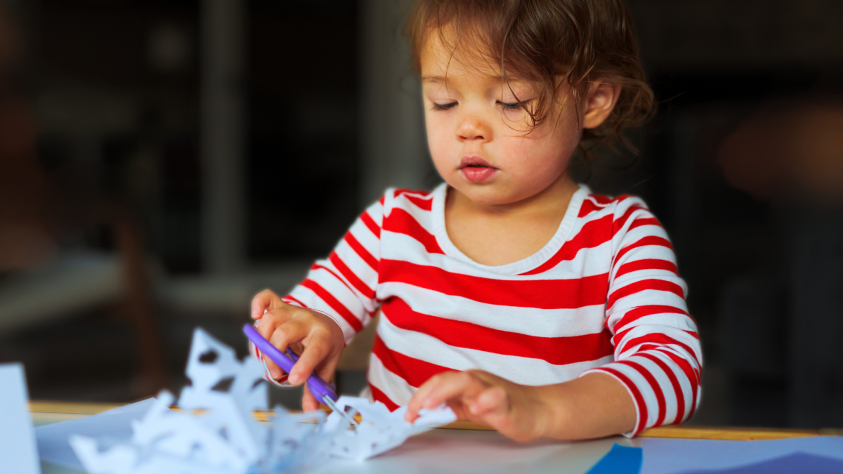 Child cutting a snowflake out of paper.