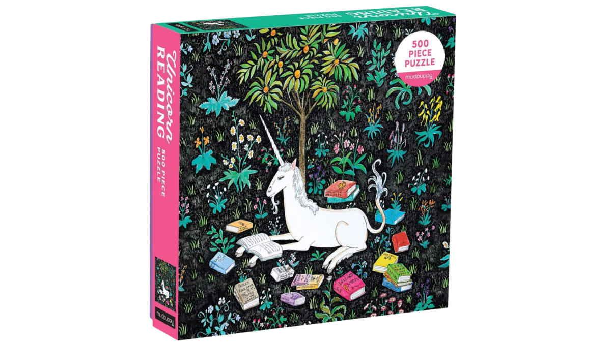 A jigsaw puzzle box with an image of a unicorn in a forest surrounded by books.